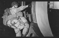 D-Day Paratrooper - A heavily burdened paratrooper, armed with a Thompson M1 submachine gun, climbs into a transport plane bound for France.