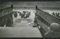 D-Day LCVP - Assault troops approach Omaha Beach, June 6, 1944. The original caption for this iconic US Coast Guard image reads 'INTO THE JAWS OF DEATH — Down the ramp of a Coast Guard landing barge Yankee soldiers storm toward the beach-sweeping fire of Nazi defenders in the D-Day invasion of the French Coast. Troops ahead may be seen lying flay under the deadly machinegun resistance of the Germans. Soon the Nazis were driven back under the overwhelming invasion forces thrown in from Coast Guard and Navy amphibious craft.'