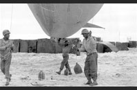 Barrage Ballons - African American soldiers of the 320th Anti-Aircraft Barrage Balloon Battalion, 1st US Army prepare to deploy a barrage balloon on Utah Beach during the Normandy invasion. US forces were racially segregated until after World War II, and the 320th was one of several African American units that landed on D-Day. The barrage balloon could be moored to the ground or to a ship by a heavy mooring cable. The combination of the heavy cable and the balloon was a simple yet effective means of preventing enemy aircraft from conducting strafing or dive-bombing attacks. Image courtesy of National Archives, 111-SC-191713